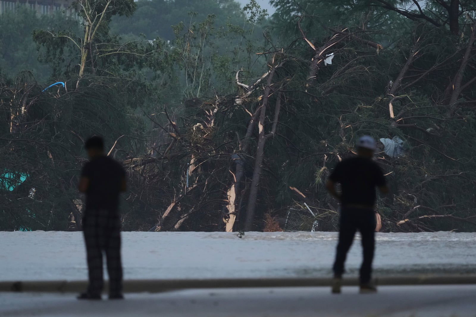 Onlookers survey damage caused along the Guadalupe River after a flash flood swept through the area, Friday, July 4, 2025, in Kerrville, Texas. (AP Photo/Eric Gay)