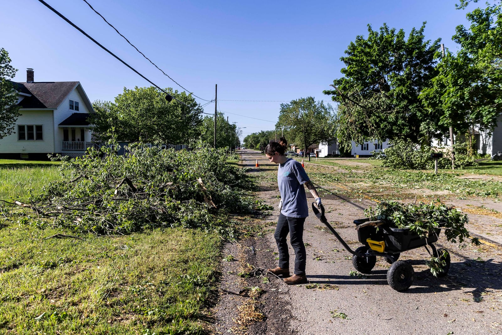 Zeeland resident Maddie Pellegrini clears debris outside her family's home on 64th Avenue in Drenthe east of Zeeland, Mich. on Friday, May 16, 2025. (Isaac Ritchey/The Grand Rapids Press via AP)