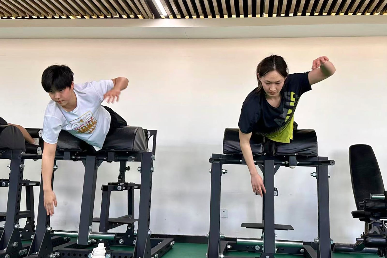 In this photo taken Jan. 15, 2025, and released by Hebei Taihua Jinye Swimming Club, 12 years old Chinese swimmer Yu Zidi, left and teammate Li Bingjie, right train together in the land training room at Hebei Taihua Jinye Swimming Club in Hengshui city, Hebei province, China. (Hebei Taihua Jinye Swimming Club via AP)