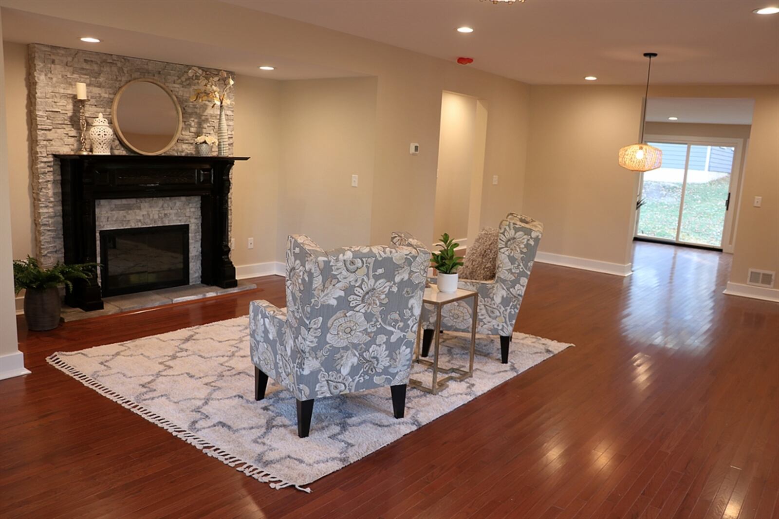 The spacious living room has a box bay window that looks out over the side yard. Tucked within a nook is a gas fireplace with stacked stone surround, a tile hearth and an ornate wood mantel. Contributed photo by Kathy Tyler