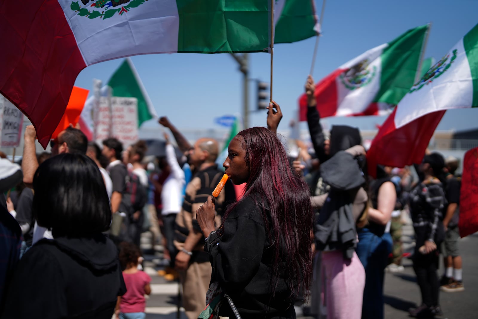 A protester cools down with an icicle while joining other protesters waving Mexican National Flags during a protest to denounce ICE, U.S. Immigration and Customs Enforcement, operations in the area Tuesday, June 10, 2025, in downtown Los Angeles. (AP Photo/Eric Thayer)
