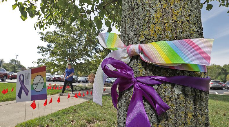 Purple ribbons are tied around trees at Clark State to bring attention to domestic violence and rainbow ribbons to stop bullying Monday. BILL LACKEY/STAFF