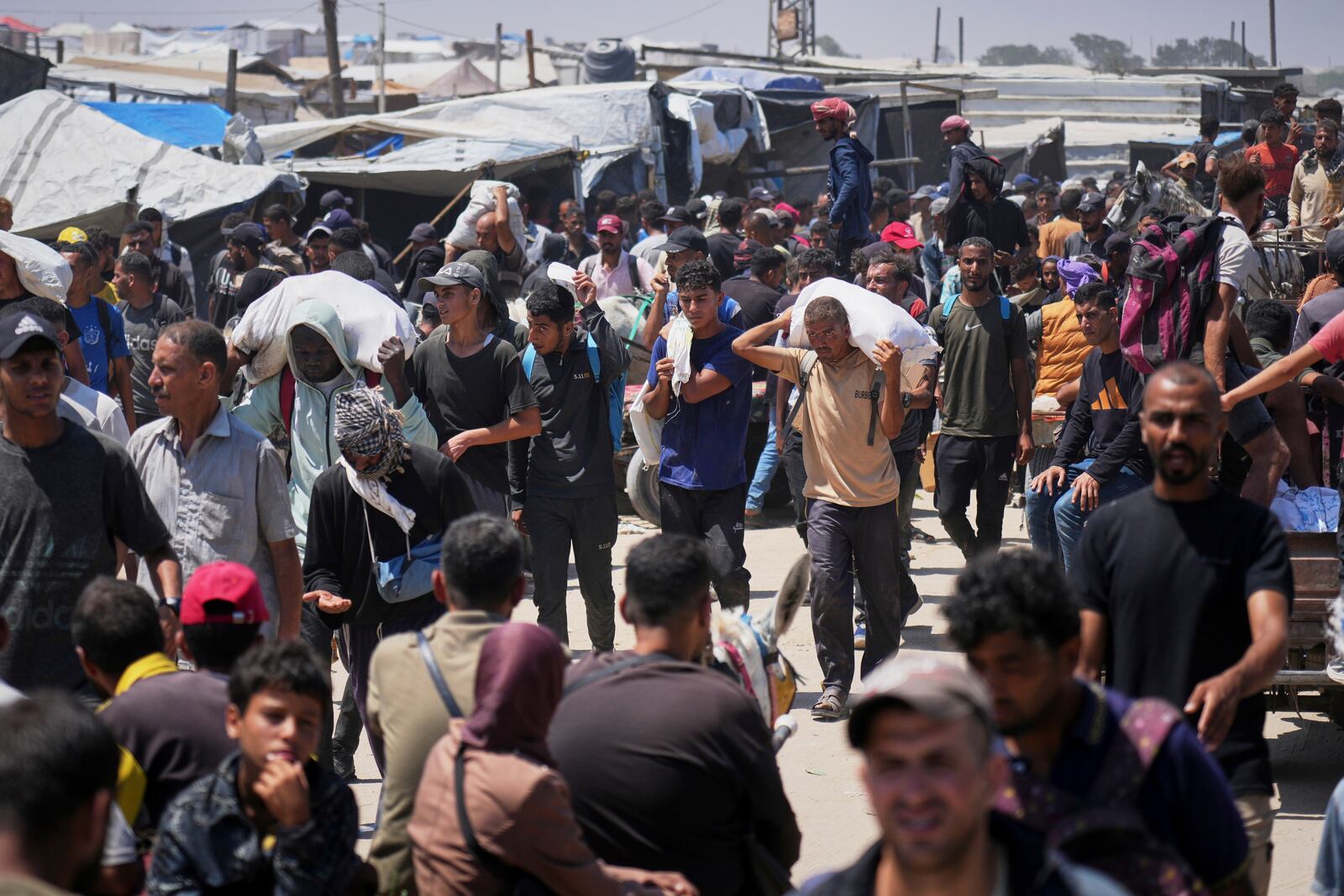 Palestinians carry bags containing food and humanitarian aid packages delivered by the Gaza Humanitarian Foundation, a U.S.-backed organization, in Rafah, southern Gaza Strip, Sunday, June 15, 2025. (AP Photo/Abdel Kareem Hana)
