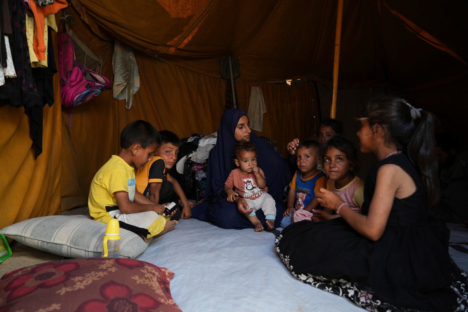 Maryam Abu Shaar, 29, sits with her children inside their tent at a camp for displaced Palestinians in Mawasi Khan Younis, Gaza Strip, on the first day of Eid al-Adha, Friday, June 6, 2025. (AP Photo/Abdel Kareem Hana)