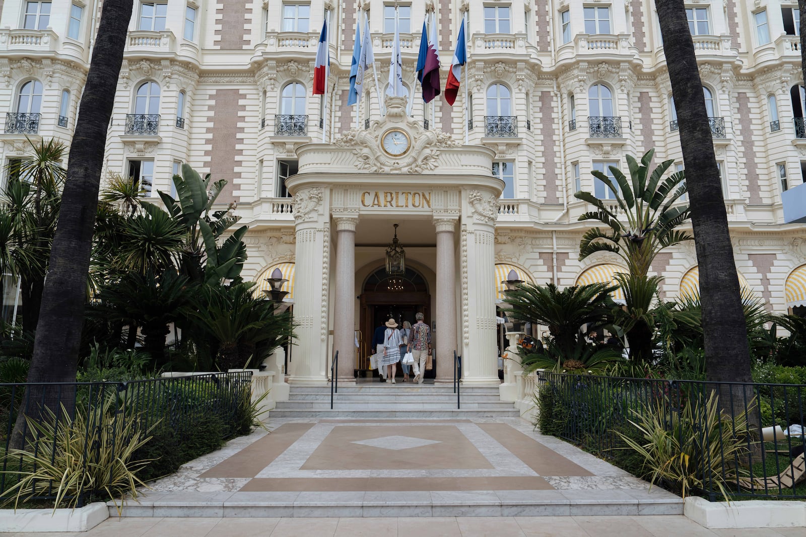 People enter the Carlton Hotel along the Boulevard de la Croisette ahead of the 78th international film festival in Cannes, southern France, Sunday, May 11, 2025. The Cannes film festival runs from May 13 until May 24, 2025. (AP Photo/Lewis Joly)