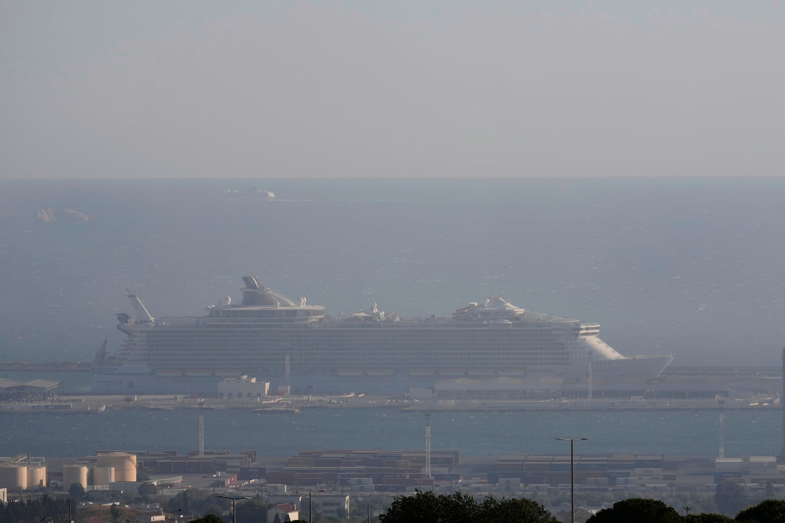 A cruise ship is seen through the smoke during a wild fire Tuesday, July 8, 2025 in the port of Marseille, southern France. (AP Photo/Lewis Joly)