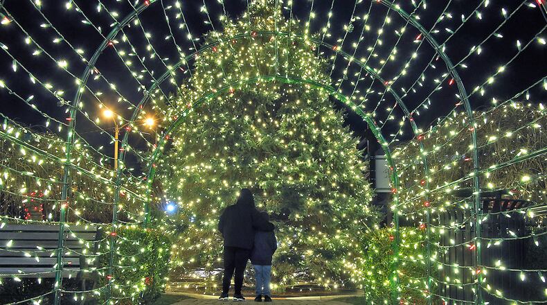 Jonathan Perrin, Jr. puts his arm around his son, Jonathan Perrin III, as they look over the Springfield's Holiday Tree Monday evening, Nov. 27, 2023. The tree and the esplanade have been covered in thousands of tiny white and red lights for the holiday. The lights were turned on officially Nov. 24 during the Grand Illumination. BILL LACKEY/STAFF