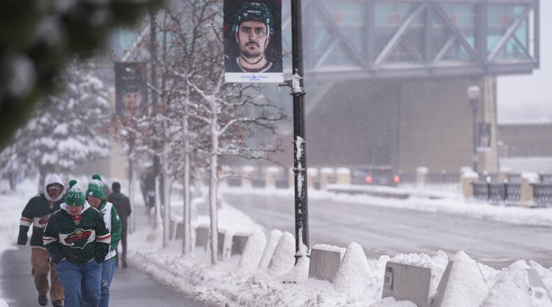 Fans walk through snowy streets before an NHL hockey game between the Minnesota Wild and Toronto Maple Leafs, Sunday, March 15, 2026, in St. Paul. (AP Photo/Abbie Parr)