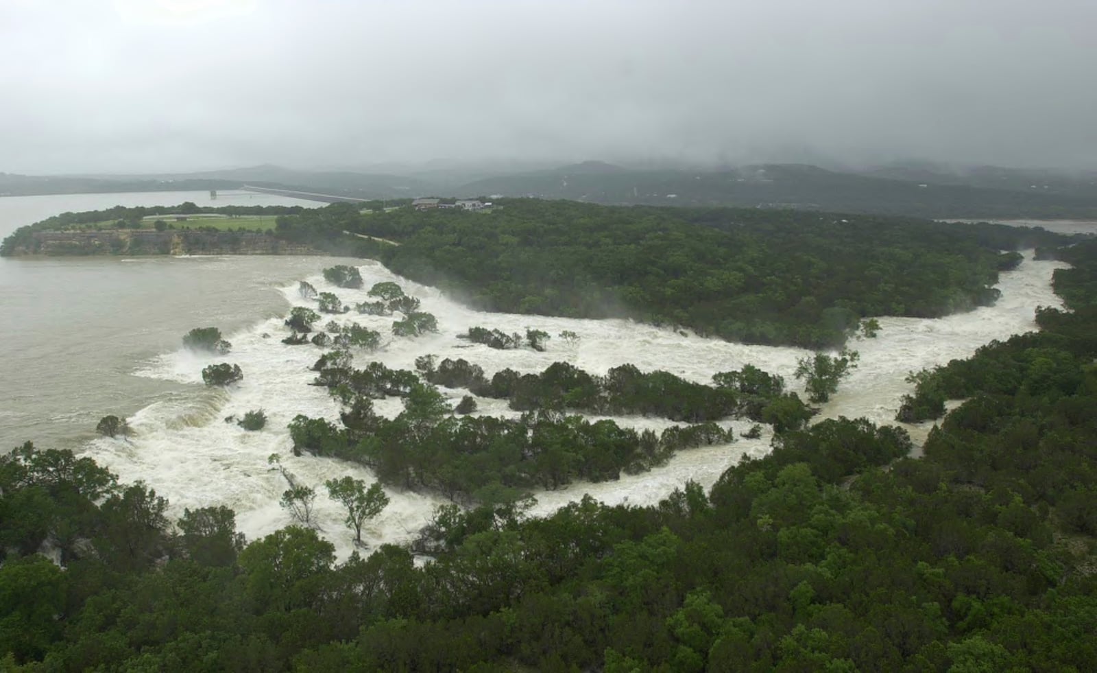 FILE - Water overflows from the Canyon Lake spillway near New Braunfels, Texas, Friday, July 5, 2002, adding to the flood waters along the Guadalupe River. (AP Photo/Eric Gay, File)