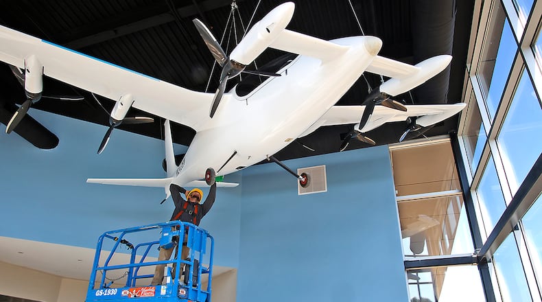 Owen Flannery, an employee with the City of Springfield, cleans the electric vertical take off and landing aircraft that hangs in the lobby of the new National Advanced Air Mobility Center of Excellence at Springfield-Beckley Municipal Airport Thursday, Sept. 14, 2023. BILL LACKEY/FILE