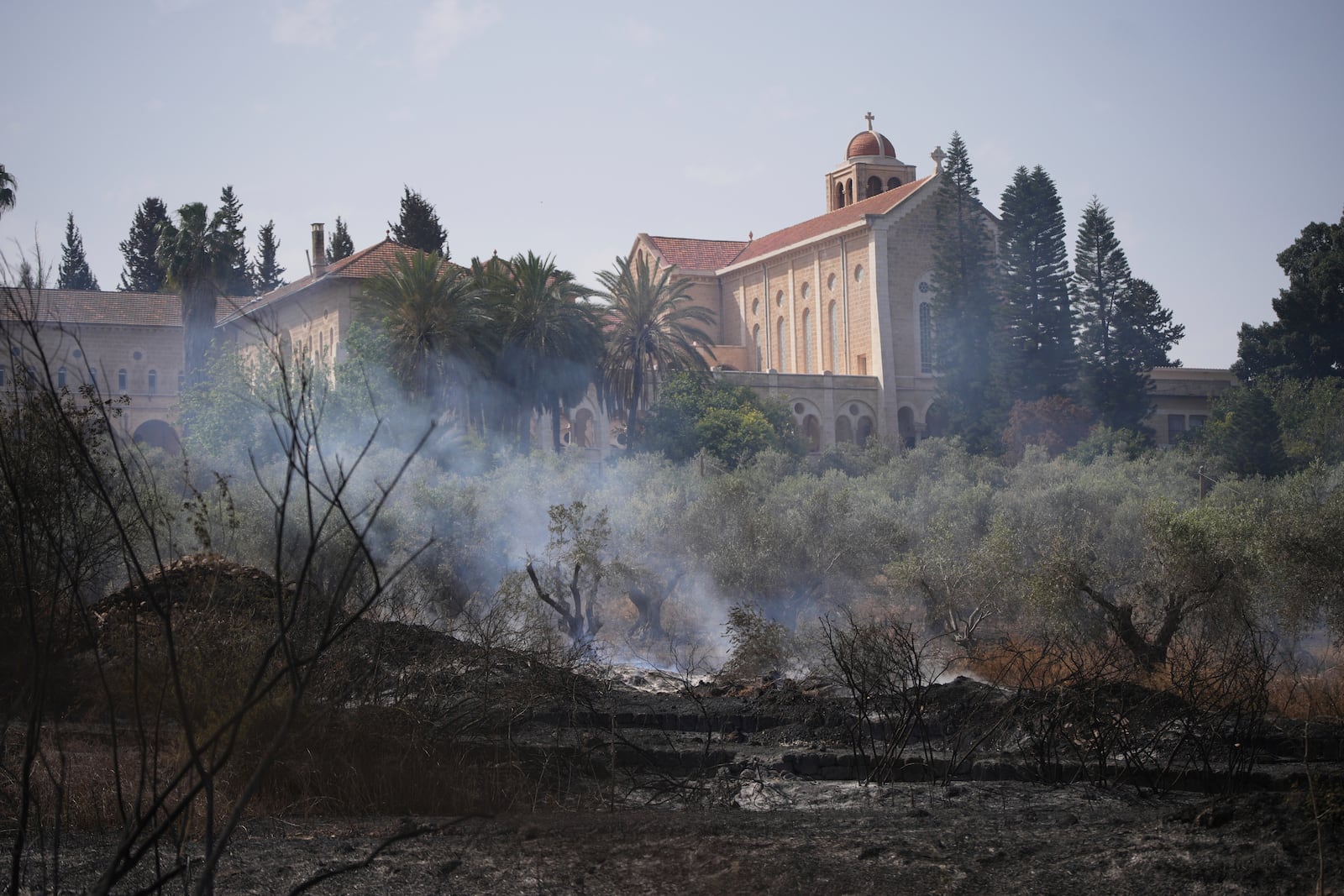 Fire smolders outside of the Roman Catholic Trappist monastery where Israeli fire crew is battling a wild fire in Latrun, Israel, outside of Jerusalem Thursday, May 1, 2025. (AP Photo/Ohad Zwigenberg)