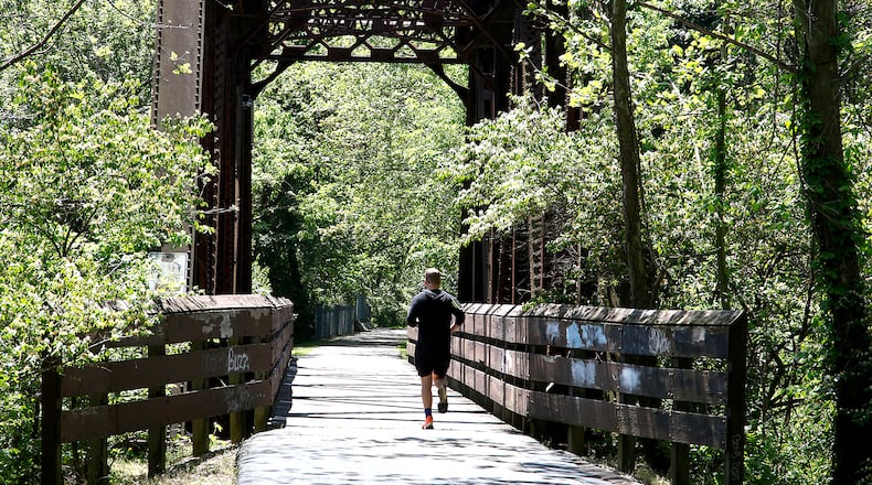 A man jogs across the steel bridge on the Simon Kenton Trail south of Mitchell Boulevard in May 2024. BILL LACKEY/STAFF