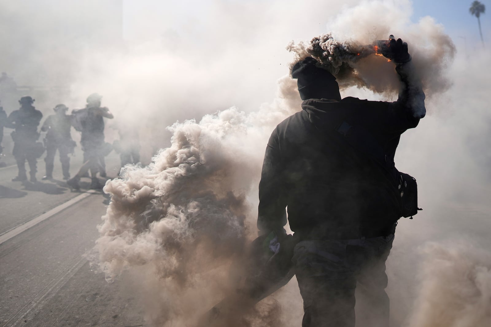 A protesters throws a smoke canister on the 101 Freeway nears the metropolitan detention center of downtown Los Angeles, Sunday, June 8, 2025, following last night's immigration raid protest. (AP Photo/Eric Thayer)