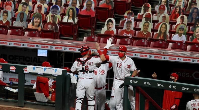 Reds catcher Tucker Barnhart, center, slaps hands with Curt Casali after the final out of the eighth inning on Monday, Aug. 3, 2020, during a game against the Indians at Great American Ball Park. David Jablonski/Staff