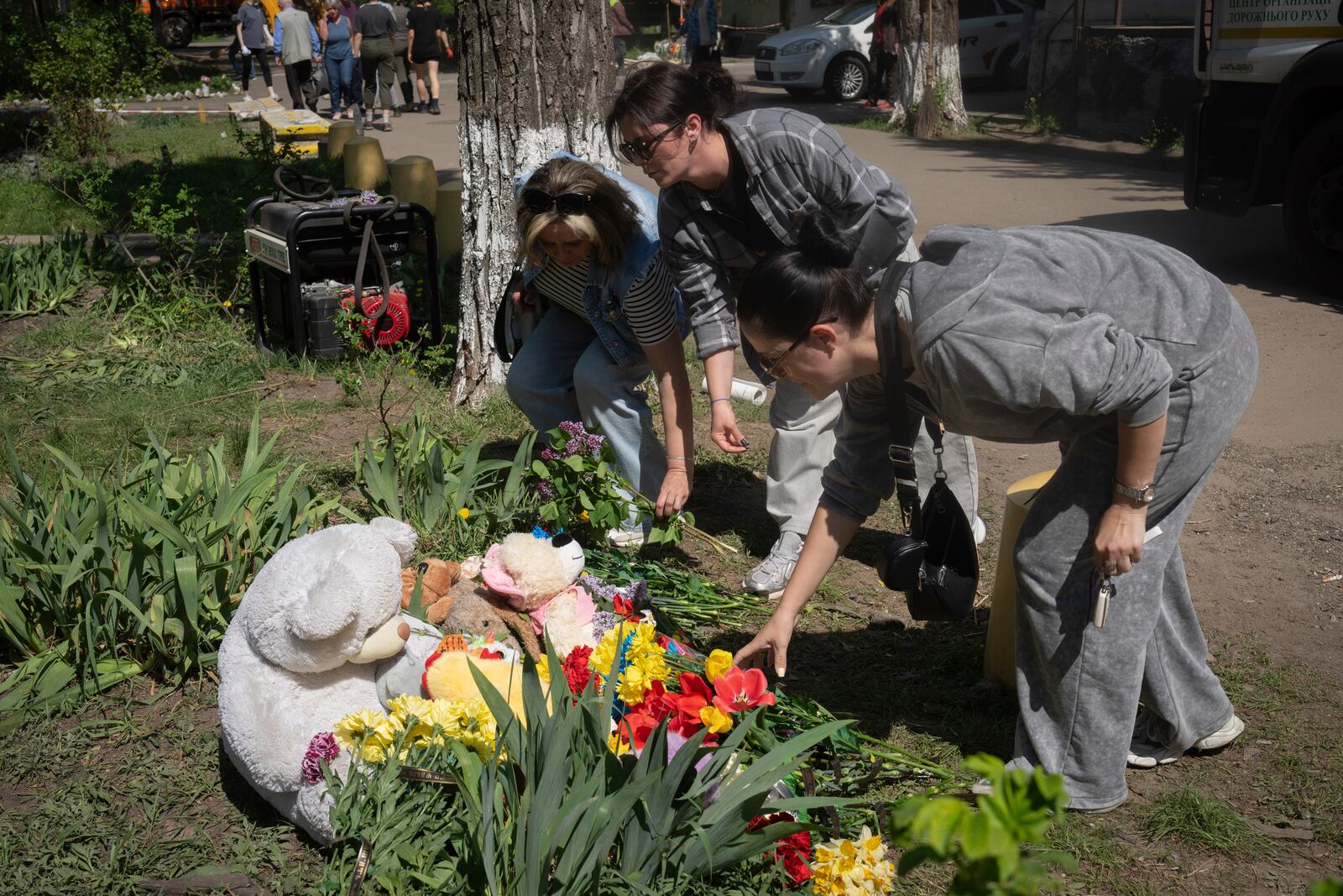 People lay flowers and toys on the site of Russia's deadly missile attack that hit residential houses Thursday killing 12 civilians and injuring 87 in Kyiv, Ukraine, Friday, April 25, 2025. (AP Photo/Efrem Lukatsky)