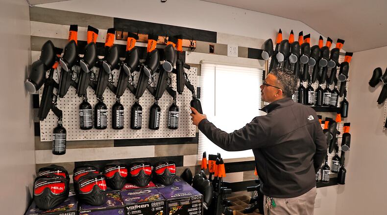 Alex Robinson hangs one of the paintball guns up in the office at his new business, Elite Paintballing, on Yellow Springs Street in Springfield. BILL LACKEY/STAFF