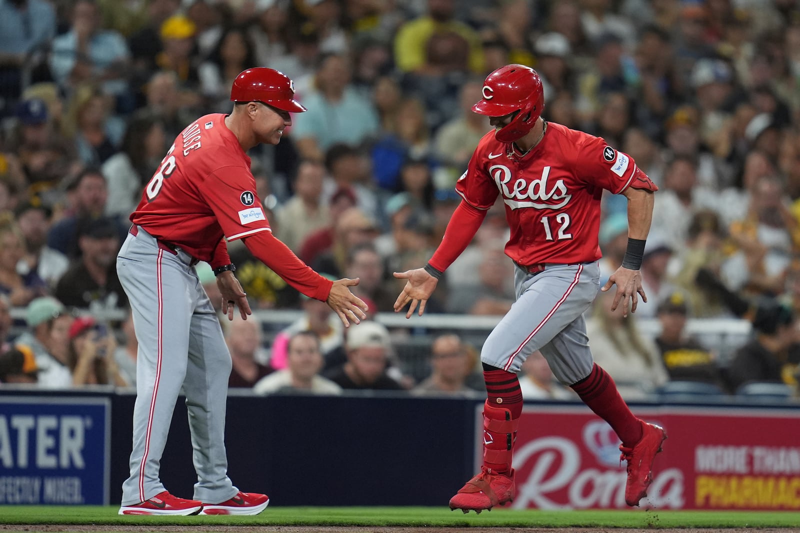 Cincinnati Reds' Austin Hays (12) celebrates with third base coach J.R. House after hitting a home run during the sixth inning of a baseball game against the San Diego Padres Monday, Sept. 8, 2025, in San Diego. (AP Photo/Gregory Bull)