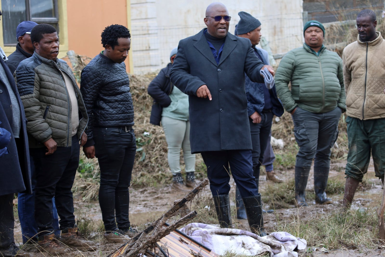 Eastern Cape premier Oscar Mabuyane, center, with local government officials stands in front of a recovered body after floods swept through the area, in Mthatha, South Africa, Wednesday, June 11, 2025. (AP Photo/Hoseya Jubase)
