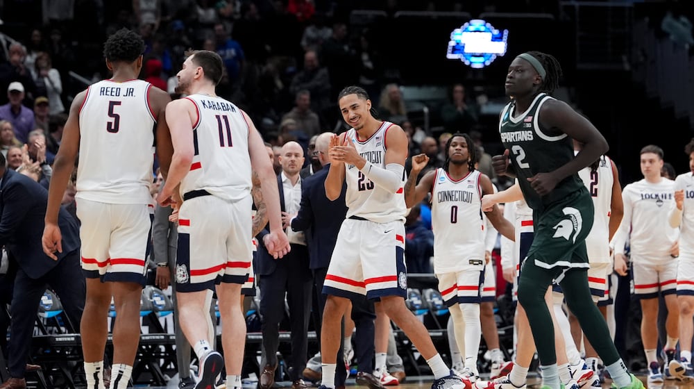 UConn forward Jayden Ross (23) celebrates with forward Tarris Reed Jr. (5) and forward Alex Karaban (11) against Michigan State during the second half in the Sweet 16 of the NCAA college basketball tournament, Saturday, March 28, 2026, in Washington. (AP Photo/Stephanie Scarbrough)