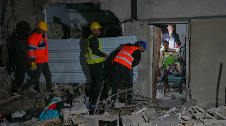 Residents carry personal belongings as they leave a building damaged in a missile strike in Tel Aviv, Israel, early Saturday, March 28, 2026. (AP Photo/Maya Levin)