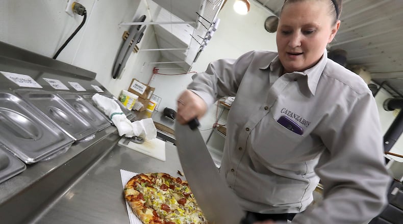 Catanzaro’s employee, Jennie Lanum, slices up a pizza in the kitchen. BILL LACKEY/STAFF