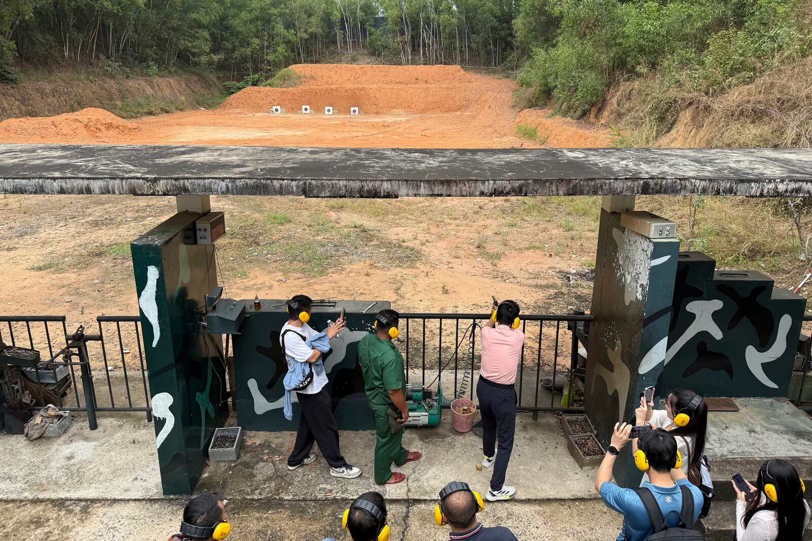 A tourist shoots targets with a war-era weapon at a firing range near Cu Chi tunnels in Ho Chi Minh City, Vietnam, Feb. 23, 2025. (AP Photo/Hau Dinh)