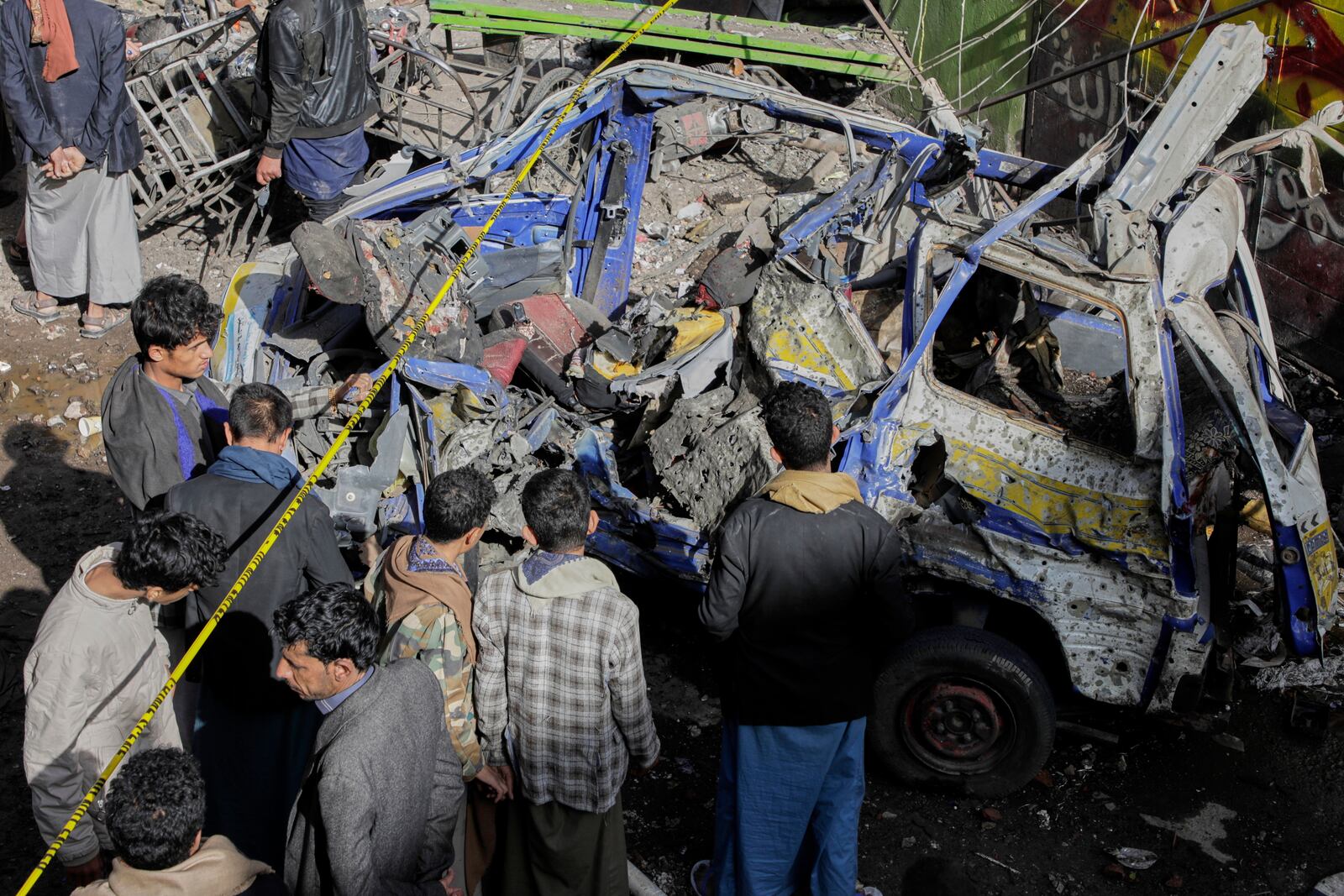 Yemenis watch a damaged vehicle at Farwah popular market which Houthis said it was struck by U.S. airstrikes in Sanaa, Yemen, Monday, April 21, 2025. (AP Photo