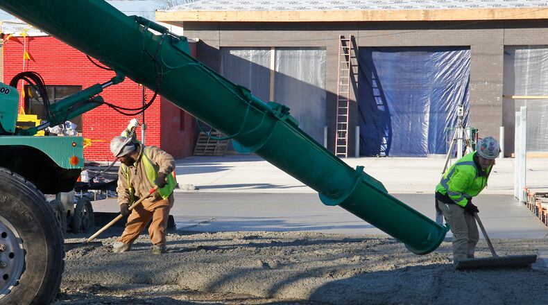 Workers smooth out the concrete as it's poured at the rear on the new Springfield Fire Station under construction along South Limestone Street Wednesday, Dec. 20, 2023. BILL LACKEY/STAFF