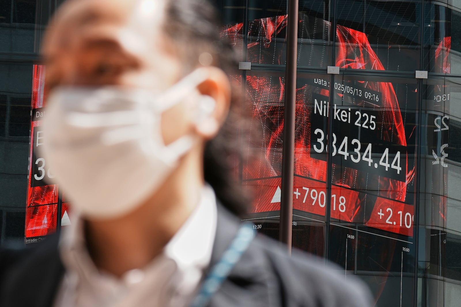 A person walks in front of an electronic stock board showing Japan's Nikkei index at a securities firm Tuesday, May 13, 2025, in Tokyo. (AP Photo/Eugene Hoshiko)