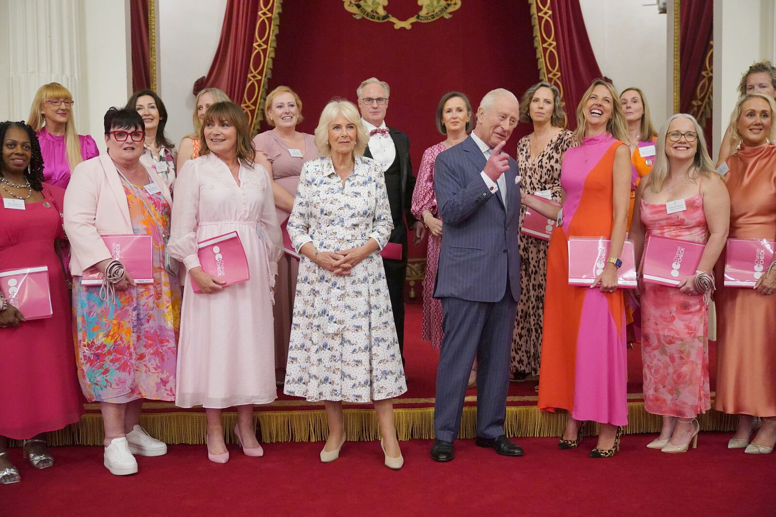 Britain's King Charles III and Queen Camilla pose for a photo with Lorraine Kelly and members of the Change and Check choir during a reception in Buckingham Palace, London, in celebration of community-based initiatives raising awareness about cancer and supporting those living with cancer, Wednesday April 30, 2025. (Yui Mok/Pool Photo via AP)