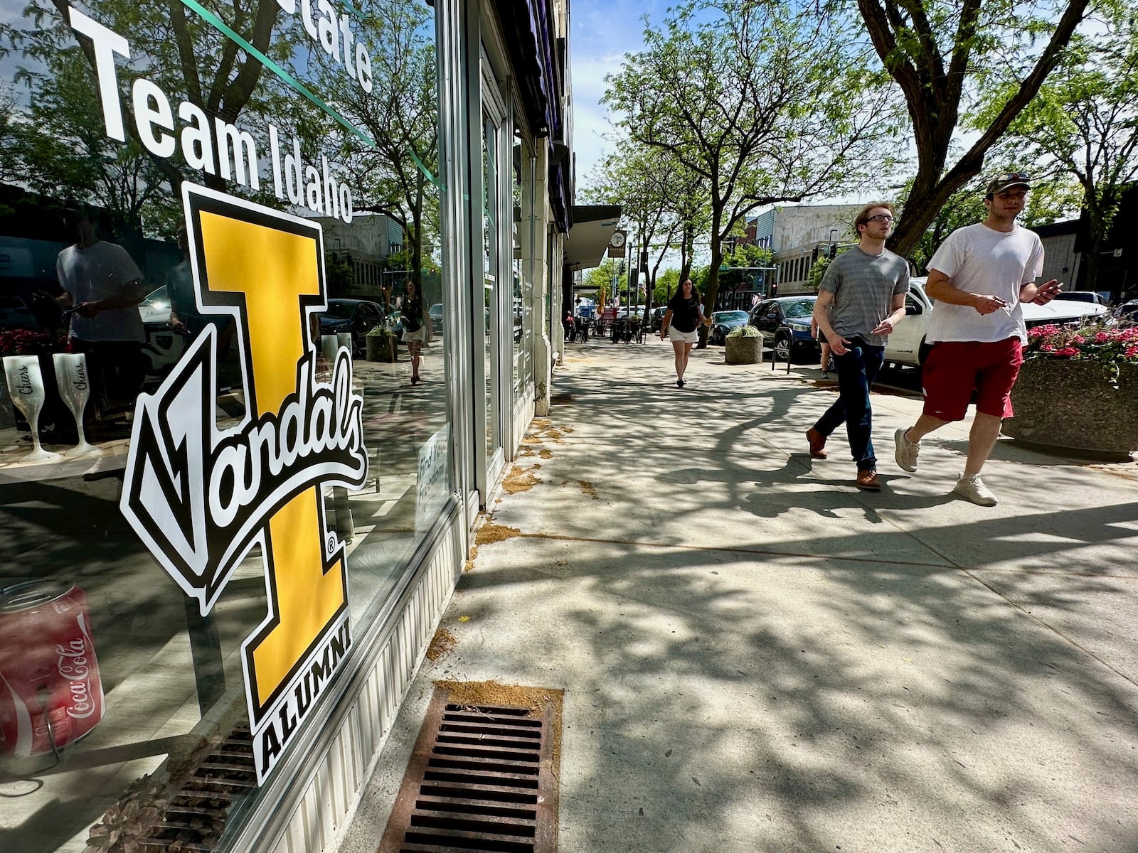 People walk on Main Street in downtown Moscow, Idaho, by a storefront with University of Idaho logo on a window on Tuesday, July 1, 2025. (AP Photos/Manuel Valdes)