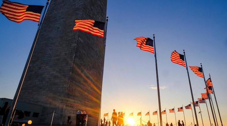 FILE - Tourists walk around the base of the Washington Monument on Presidents Day weekend as the sunsets, Feb. 19, 2017, in Washington. (AP Photo/J. David Ake, file)