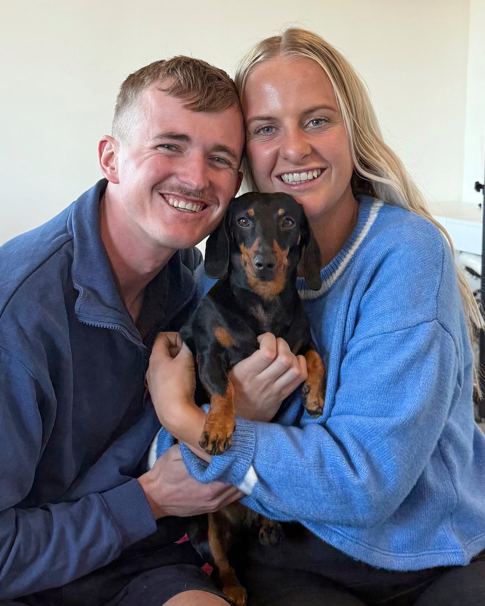 Georgia Gardner and partner Josh Fishlock hold Valerie, their miniature dachshund after being reunited on Kangaroo Island in South Australia after Valerie was missing for 540 days, Tuesday, May 6, 2025. (Ruby Stewart/The Advertiser via AP)