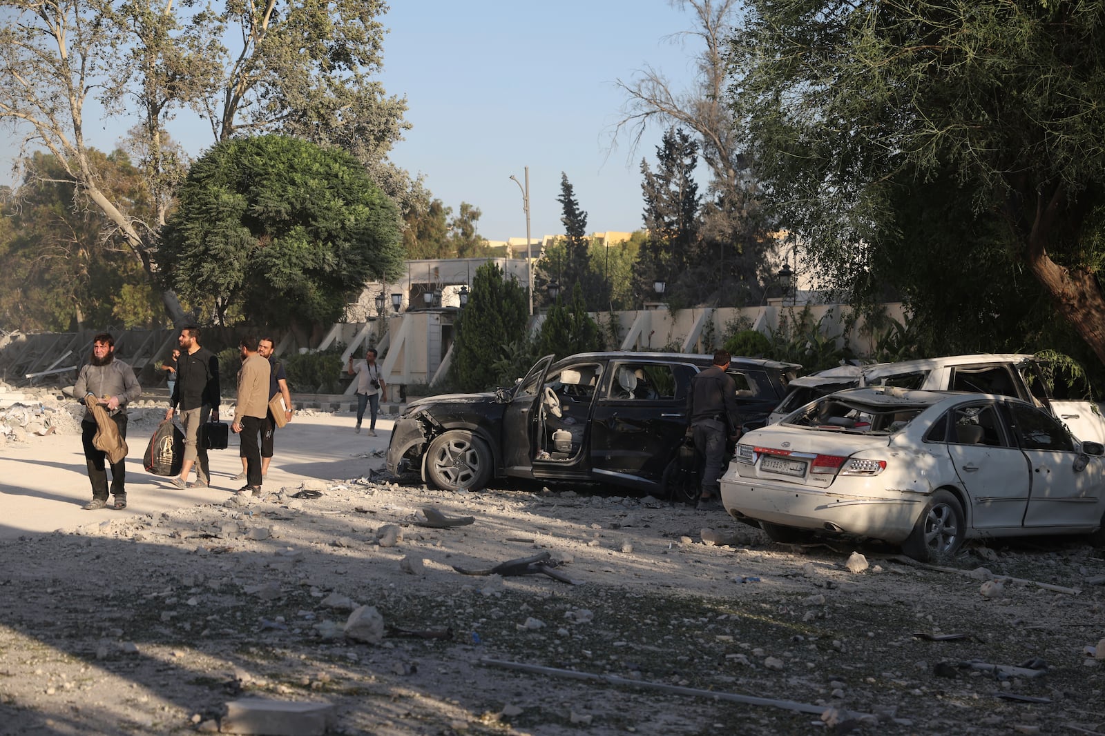 Security members carry belongings as they leave the damaged Syrian Defense Ministry building allegedly hit by several Israeli airstrikes, in Damascus, Syria, Wednesday, July 16, 2025. (AP Photo/Ghaith Alsayed)