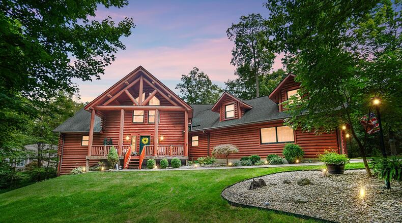 This custom story and a half log home sits on 1.3 wooded acres on the shore of Lake Sylvan in South Vienna. It has a two story covered front porch and two car attached garage. CONTRIBUTED