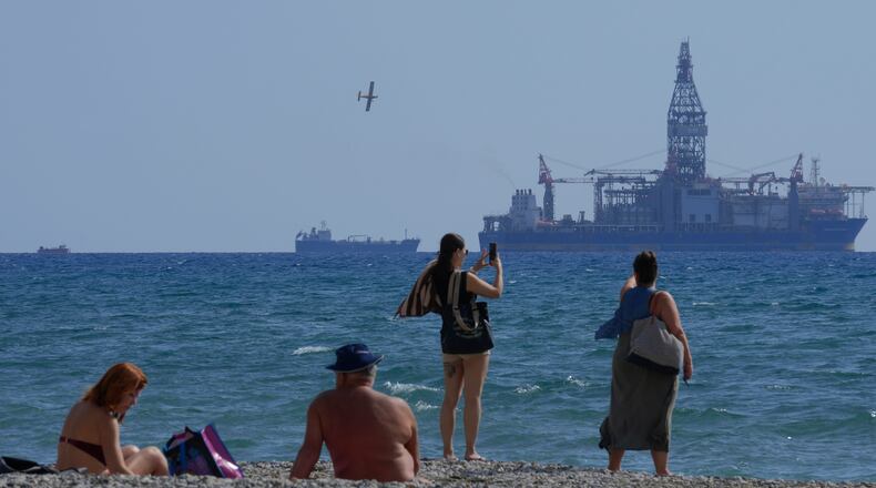 FILE - People on the beach take photos of the 'Tungsten Explorer' drilling ship, in the southern coastal city of Larnaca, Cyprus, Wednesday, Nov. 3, 2021. (AP Photo/Petros Karadjias, File)