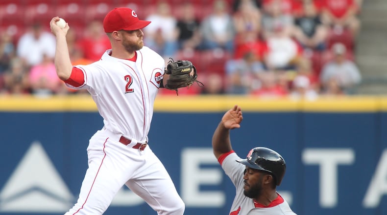 Zack Cozart turns a double play for the Reds against the Cardinals. David Jablonski/Staff