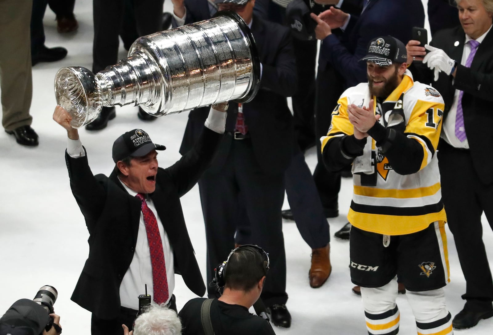 FILE - Pittsburgh Penguins head coach Mike Sullivan hoists the Stanley Cup as Bryan Rust (17) watches after defeating the Nashville Predators 2-0 in Game 6 of the NHL hockey Stanley Cup Final, Sunday, June 11, 2017, in Nashville, Tenn. (AP Photo/Jeff Roberson, file)