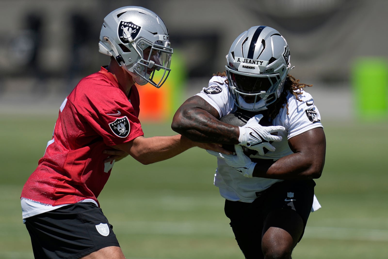 Las Vegas Raiders' quarterback Cam Miller hands off a ball to Ashton Jeanty during an NFL football rookie mini camp Friday, May 9, 2025, in Henderson, Nev. (AP Photo/John Locher)