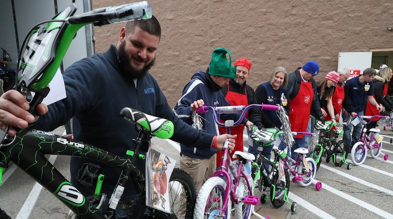 Volunteers from the Salvation Army, Rollins Moving and Storage and Walmart associates pass bicycles along a human chain as they load two semi-trucks with 154 bicycles at the Walmart on Tuttle Road Thursday. The bicycles will be destributed by the Salvation Army to needy children in Clark County this Christmas. BILL LACKEY/STAFF