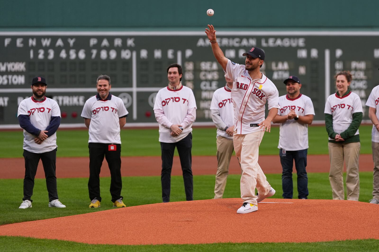 Omer Shem Tov, front, a former Israeli hostage who survived over 500 days in Hamas captivity, delivers a ceremonial first pitch prior to a baseball game between the Boston Red Sox and the New York Mets at Fenway Park, Monday, May 19, 2025, in Boston. (AP Photo/Charles Krupa)