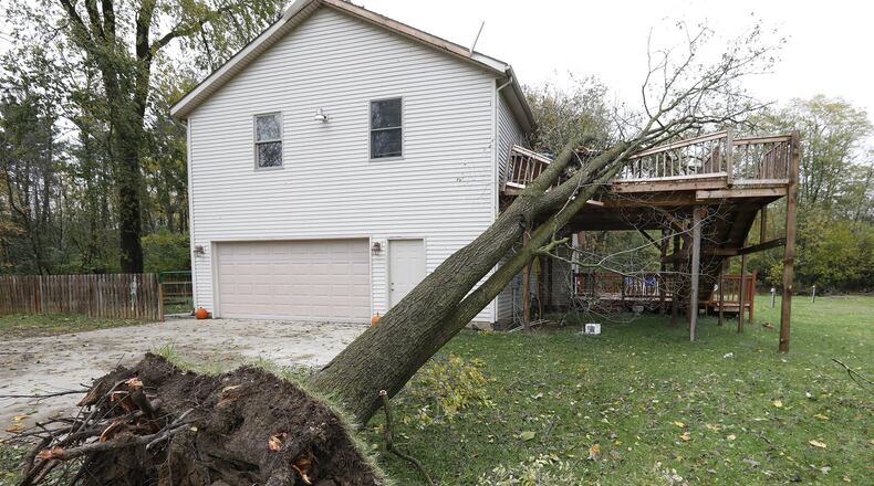 A tree rests on the second story of a deck attached to a house along Long Court in South Vienna Monday. Bill Lackey/Staff