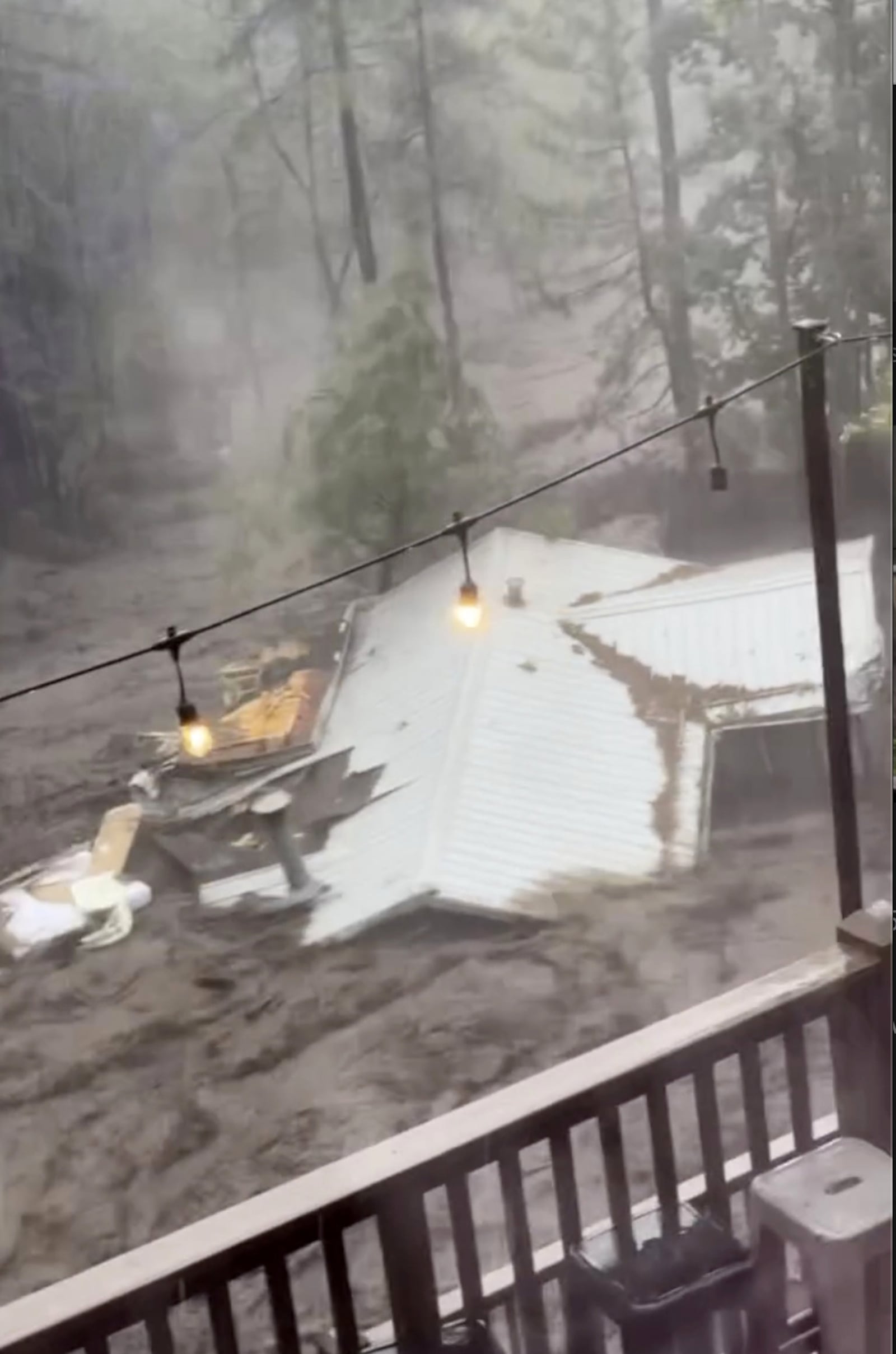 In this image taken from video, a house carried away by flash flooding is seen behind a house in Ruidoso, N.M., Tuesday, July 8, 2025. (Kaitlyn Carpenter via AP)