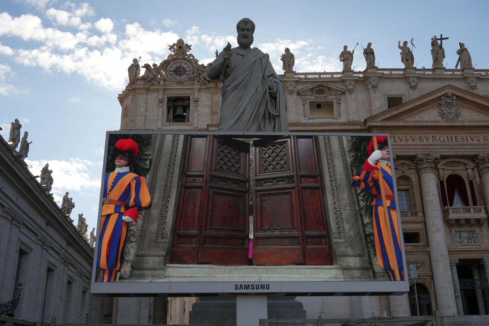A giant screen in St Peter's Basilica shows a Vatican official closing the door to the Sistine Chapel after calling out "extra omnes", Latin for "all out", during the cardinals' conclave to elect a new pope, at the Vatican, Wednesday, May 7, 2025.(AP Photo/Alessandra Tarantino)