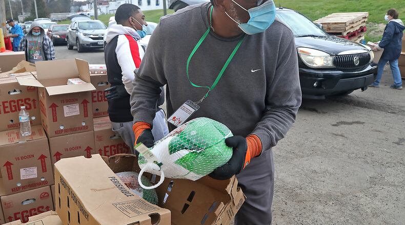 Volunteers at Second Harvest Food Bank fill up the trunks of cars with food for Thanksgiving Wednesday. A line of cars stretched for several blocks as people in need waited for food. BILL LACKEY/STAFF