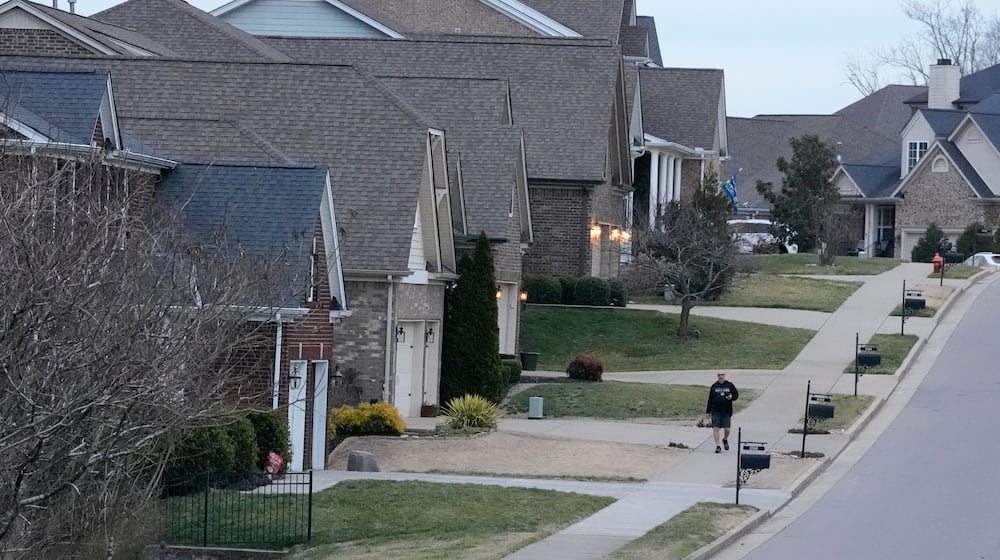 A person walks past single family homes, Tuesday, Feb. 10, 2026, in Nashville, Tenn. (AP Photo/George Walker IV)