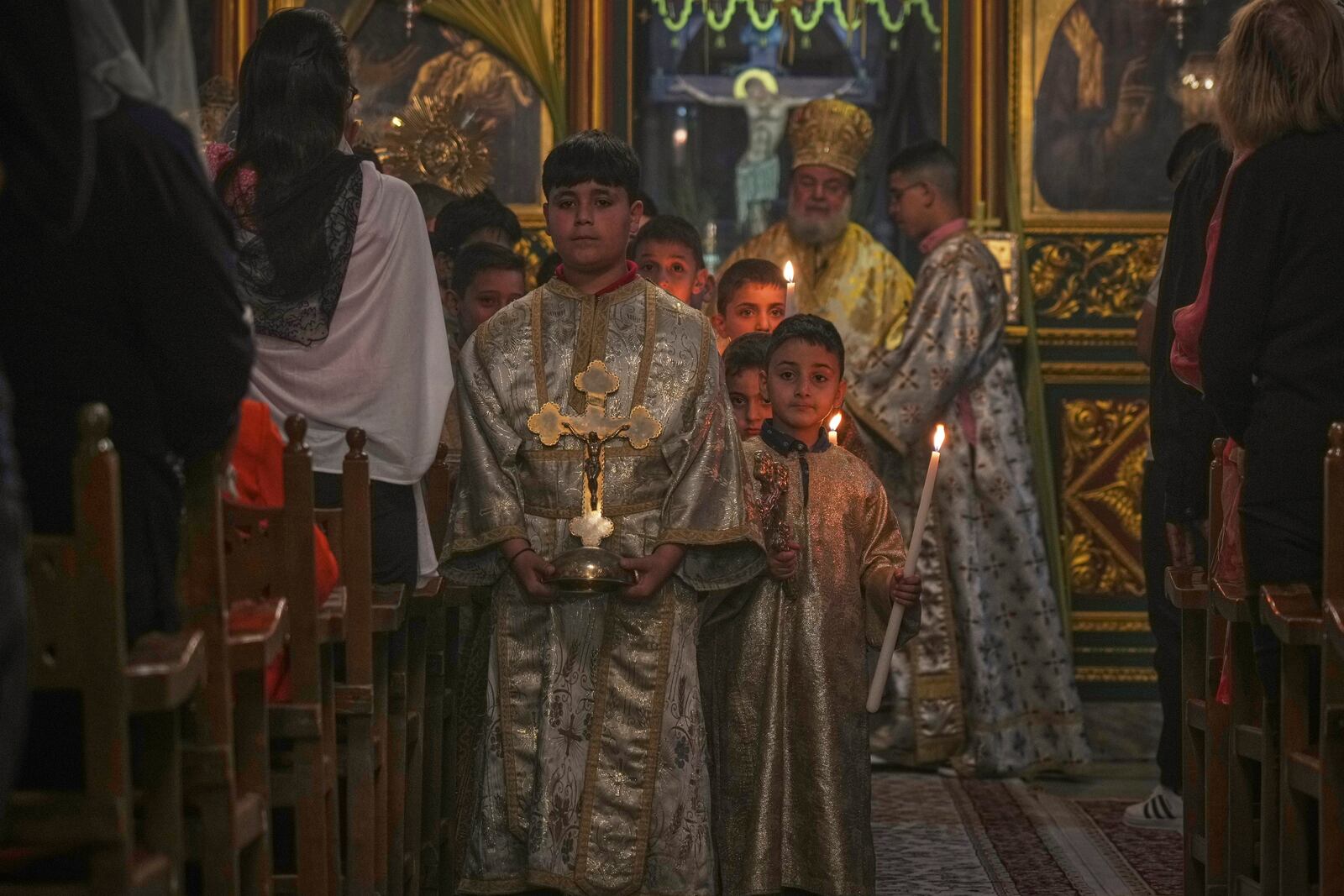 Altar boys walk down the aisle as Palestinian Christians attend a Palm Sunday mass at the Greek Orthodox Church of Saint Porphyrius in Gaza City, Sunday, April 13, 2025. (AP Photo/Jehad Alshrafi)