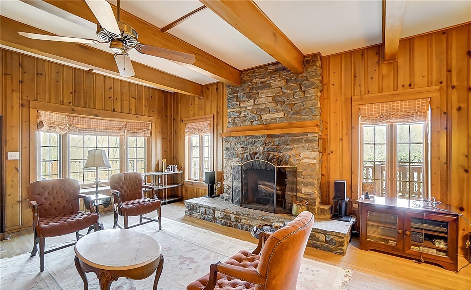 The family room addition has wood beamed ceilings and wood paneling, hardwood flooring and a floor to ceiling stone fireplace.