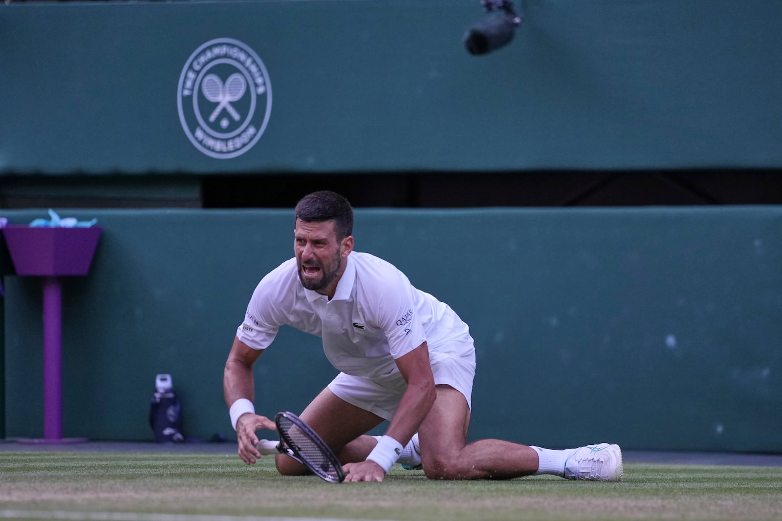 Serbia's Novak Djokovic reacts after slipping and falling when attempting a return to Italy's Flavio Cobolli during a quarterfinal men's singles match at the Wimbledon Tennis Championships in London, Wednesday, July 9, 2025. (AP Photo/Kin Cheung)