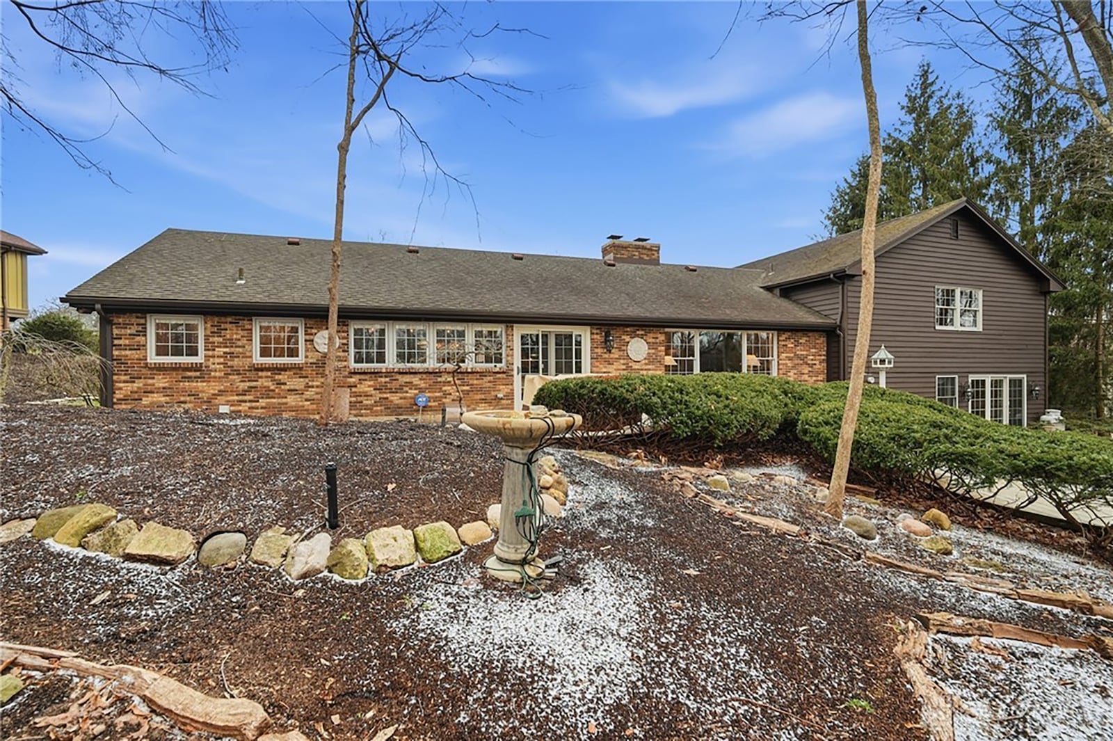 The back of the home has stone accents and mature trees. CONTRIBUTED